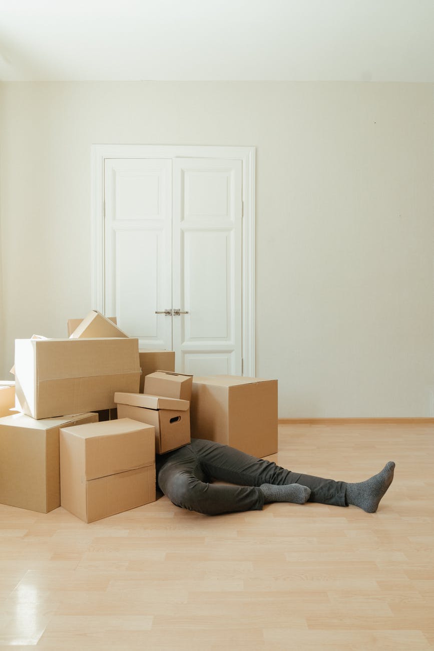 person in black leather boots sitting on brown cardboard boxes